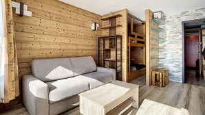 A cozy living room with a sofa, a coffee table, and built-in wooden shelves.
