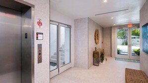 Un hall d’entrée moderne avec un comptoir d’accueil, un escalier et un ascenseur.