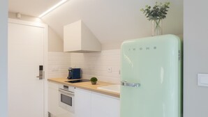 A modern kitchen with white cabinets, a light green refrigerator, and a wooden countertop.