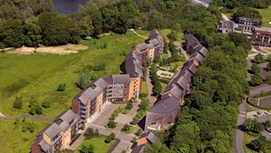 An aerial view of a residential complex with multiple apartment buildings, green spaces, and a river. - Dromroe Village University of Limerick (Limerick)