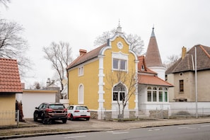 A yellow building with a red roof, a white fence, and parked cars. - Exclusive Villa an der Bode (Thale)