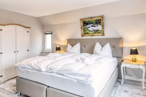 A neatly made bed with white linens, a headboard, and two bedside lamps. - Exclusive Villa an der Bode (Thale)