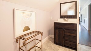 Un baño con tocador, espejo y un cuadro en la pared.
