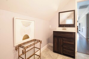 Un baño con tocador, espejo y un cuadro en la pared.