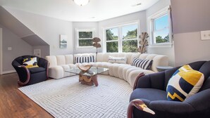 A modern living room with a sectional sofa, a glass coffee table, and a patterned rug. - Newly Renovated 1 Block from Beach w/Pool!~The Jolly Folly (Folly Beach)