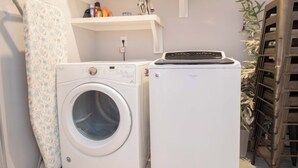 A laundry area with a front-loading washing machine and a stacked dryer. - Newly Renovated 1 Block from Beach w/Pool!~The Jolly Folly (Folly Beach)