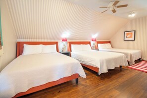 Une chambre d’hôtel avec deux lits, un ventilateur de plafond et un tableau encadré au mur.