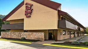 A Red Roof Inn with a stone facade, a red roof, and a parking lot.