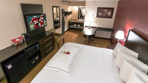 Una habitación de hotel con cama, televisión, escritorio, silla y una pequeña mesa.