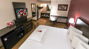 Una habitación de hotel con cama, televisión, escritorio, silla y una pequeña mesa.