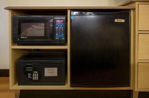 Eine Küche mit Mikrowelle, digitalem Kaffeeautomaten und Kühlschrank.