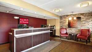 A reception area with a counter, free Wi-Fi sign, coffee station, and Red Roof Inn sign.