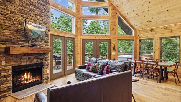A spacious living area with a stone fireplace, a leather sofa, and a dining table with chairs.