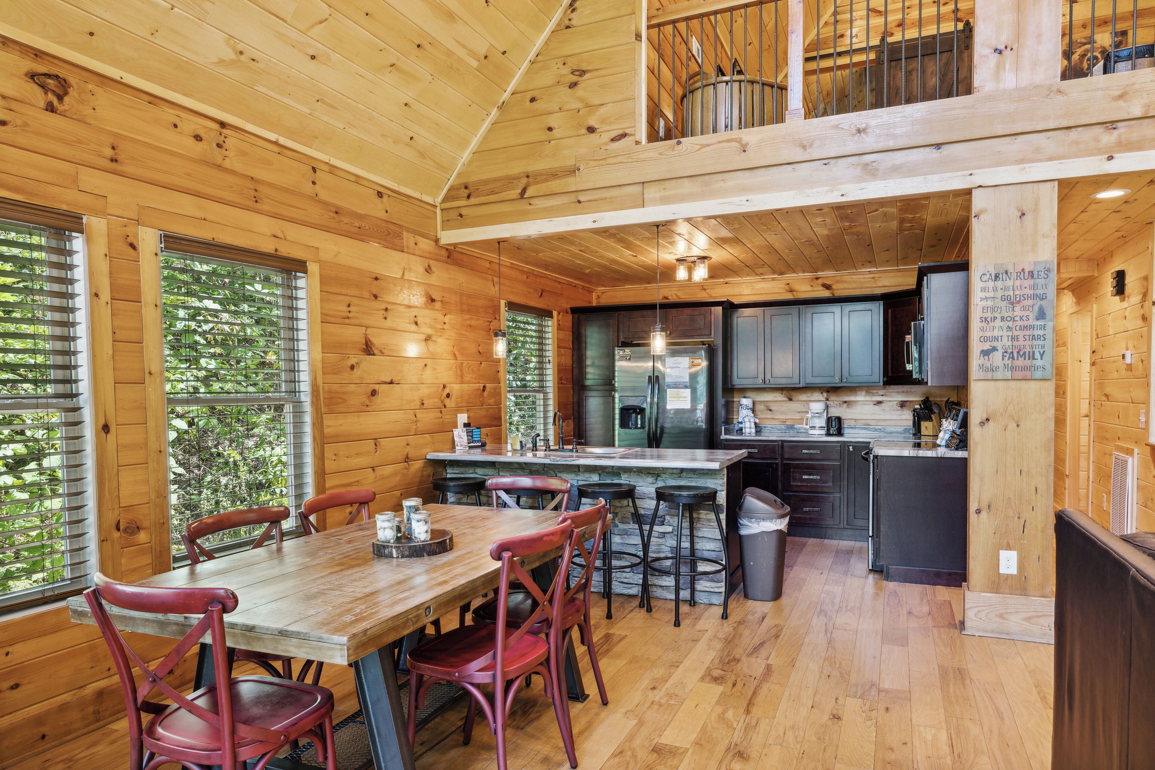 A wooden cabin interior with a dining area, kitchen, and a balcony.