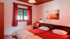 Una habitación con dos camas, una ventana con cortinas rojas, techo de madera y un cuadro colgado en la pared.