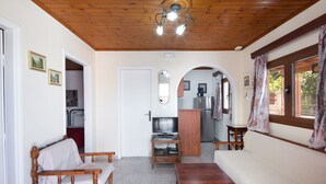 Una sala acogedora con techo de madera, un sofá, una mesa de madera y un mueble para televisión.