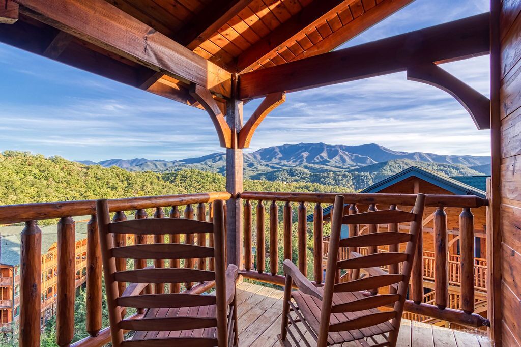 Un balcon en bois offrant une vue sur les montagnes et un bâtiment en arrière-plan.