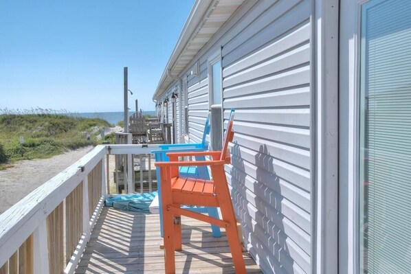 A wooden deck with a railing, a table, and two chairs.