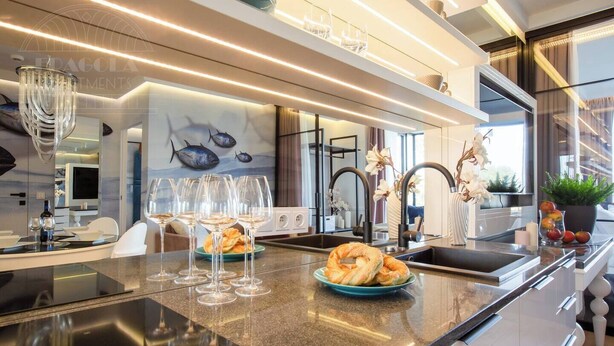 A modern kitchen with a marble countertop, wine glasses, a plate of bagels, and a fish mural on the wall. - Vistula View by Fragola Collection (Kraków)