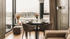 A dining area with a round table, chairs, a chandelier, and a view of buildings through large windows. - Vistula View by Fragola Collection (Kraków)