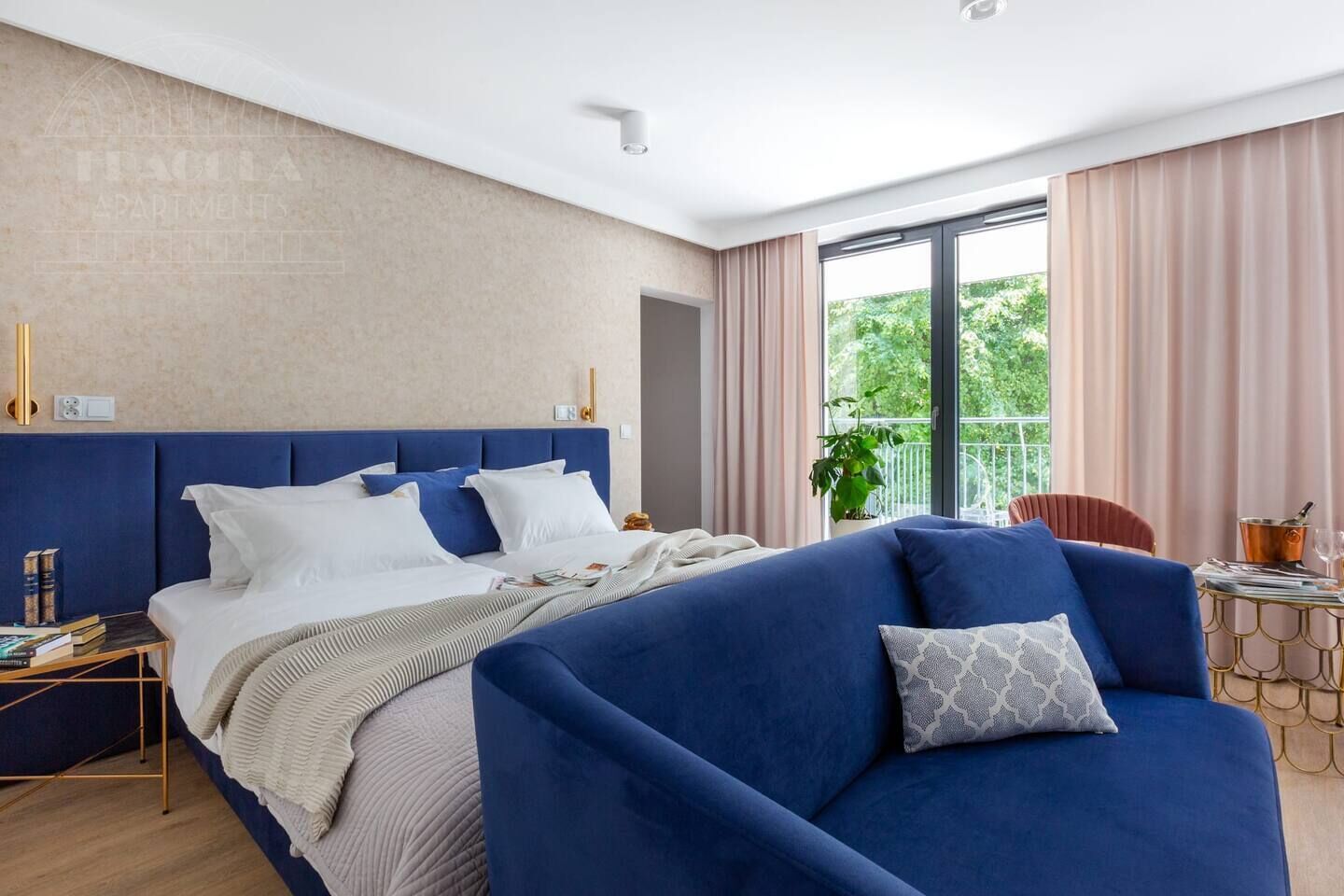 A modern bedroom with a large bed, a sofa, a small table, and a balcony with a view.