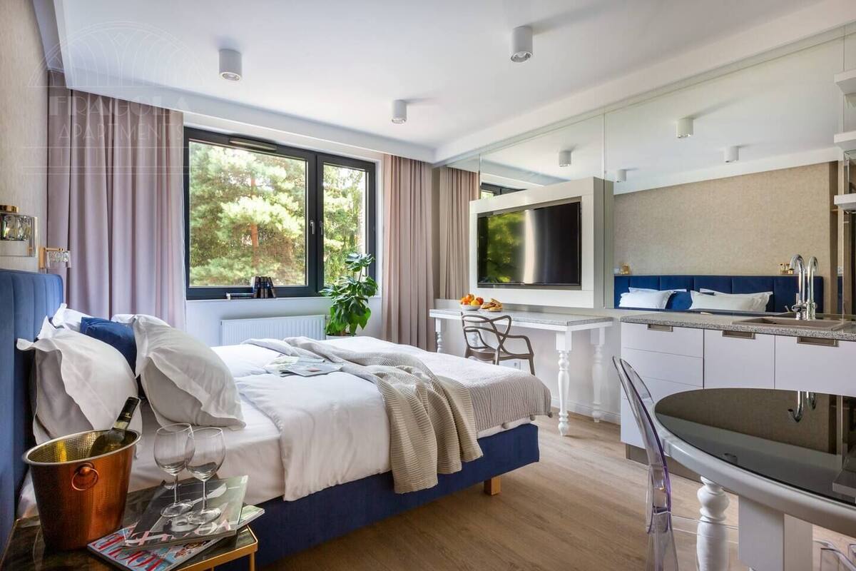 Un dormitorio moderno con cama, mesita de noche y un ventanal grande.