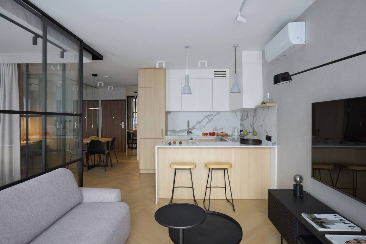 Una cocina moderna con salpicadero de mármol, armarios de madera y una isla central con taburetes.