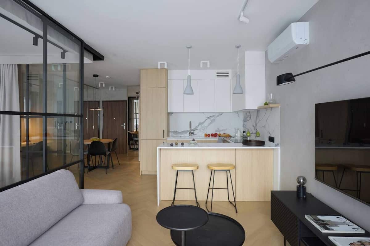 A modern kitchen with a marble backsplash, wooden cabinets, and a central island with stools.