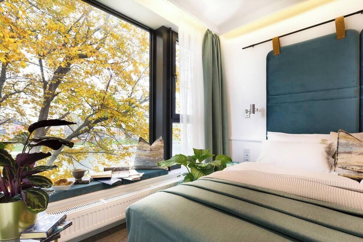 Un dormitorio moderno con un ventanal grande, una cama con cabecera y un radiador.