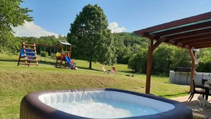 An outdoor hot tub with a wooden deck and a slide in the background. - Amazing paradise Una (Donji Lapac)