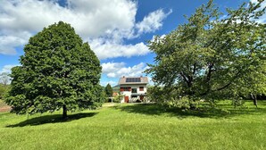 A house with a solar panel roof, surrounded by lush green trees and grass. - Amazing paradise Una (Donji Lapac)
