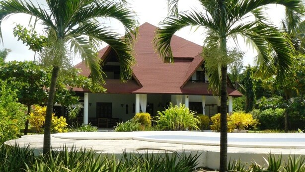 A two-story building with a red roof, surrounded by lush greenery and palm trees. - Malaika House (Malindi)