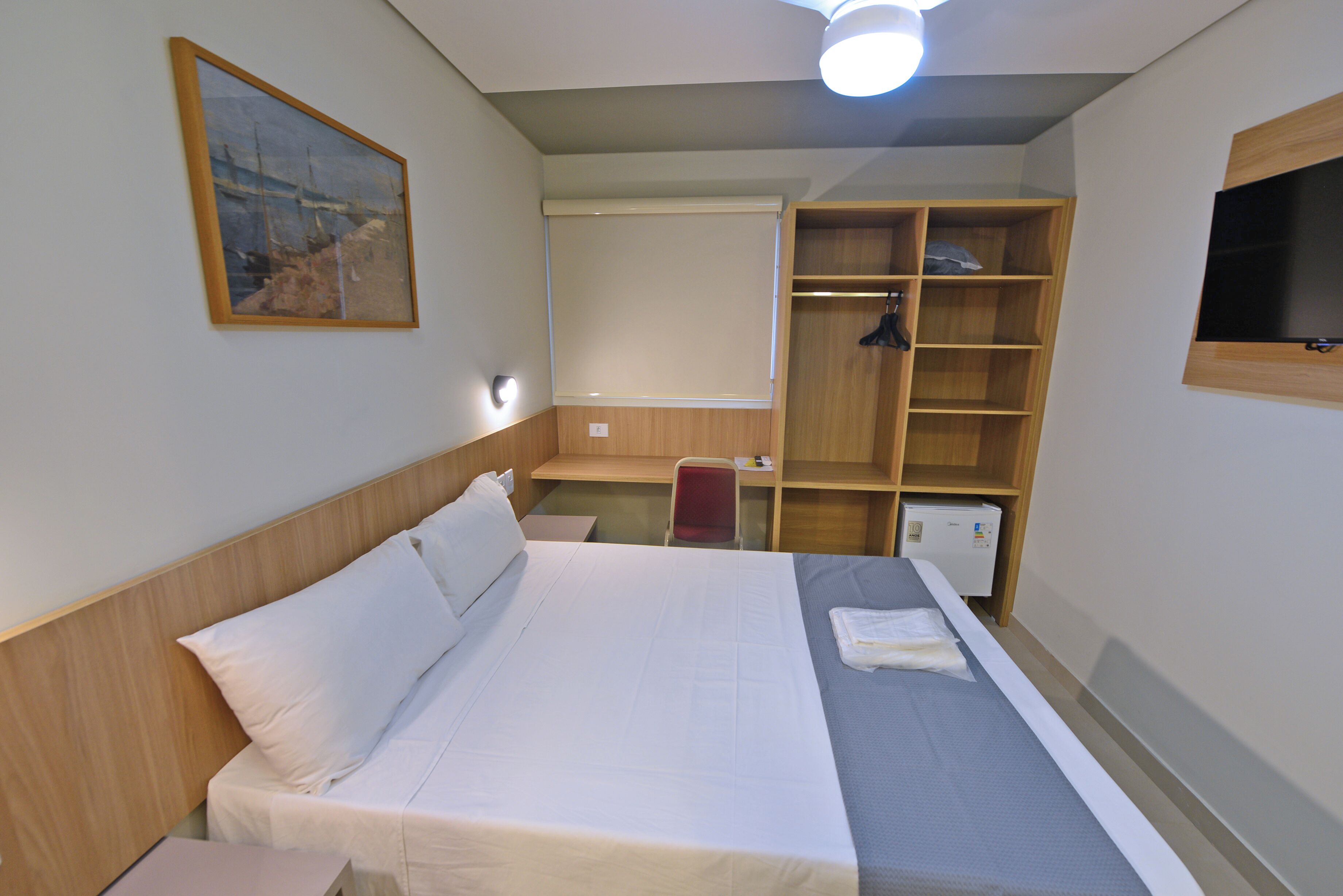 Hotellihuone, jossa on sänky, työpöytä, tuoli, vaatekaappi ja televisio.