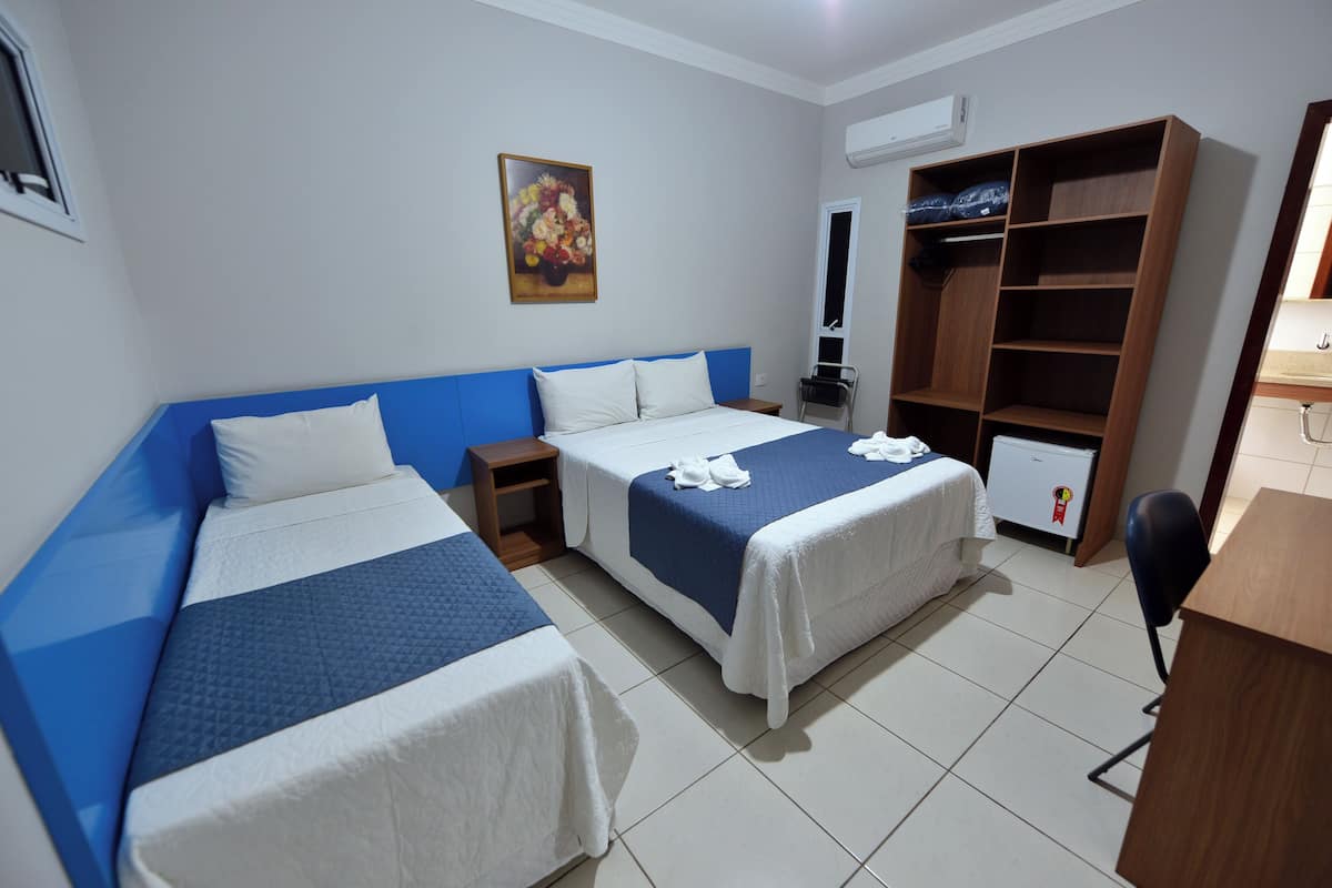 Ein Hotelzimmer mit zwei Betten, einem Kleiderschrank, einem Schreibtisch und einem Sessel.