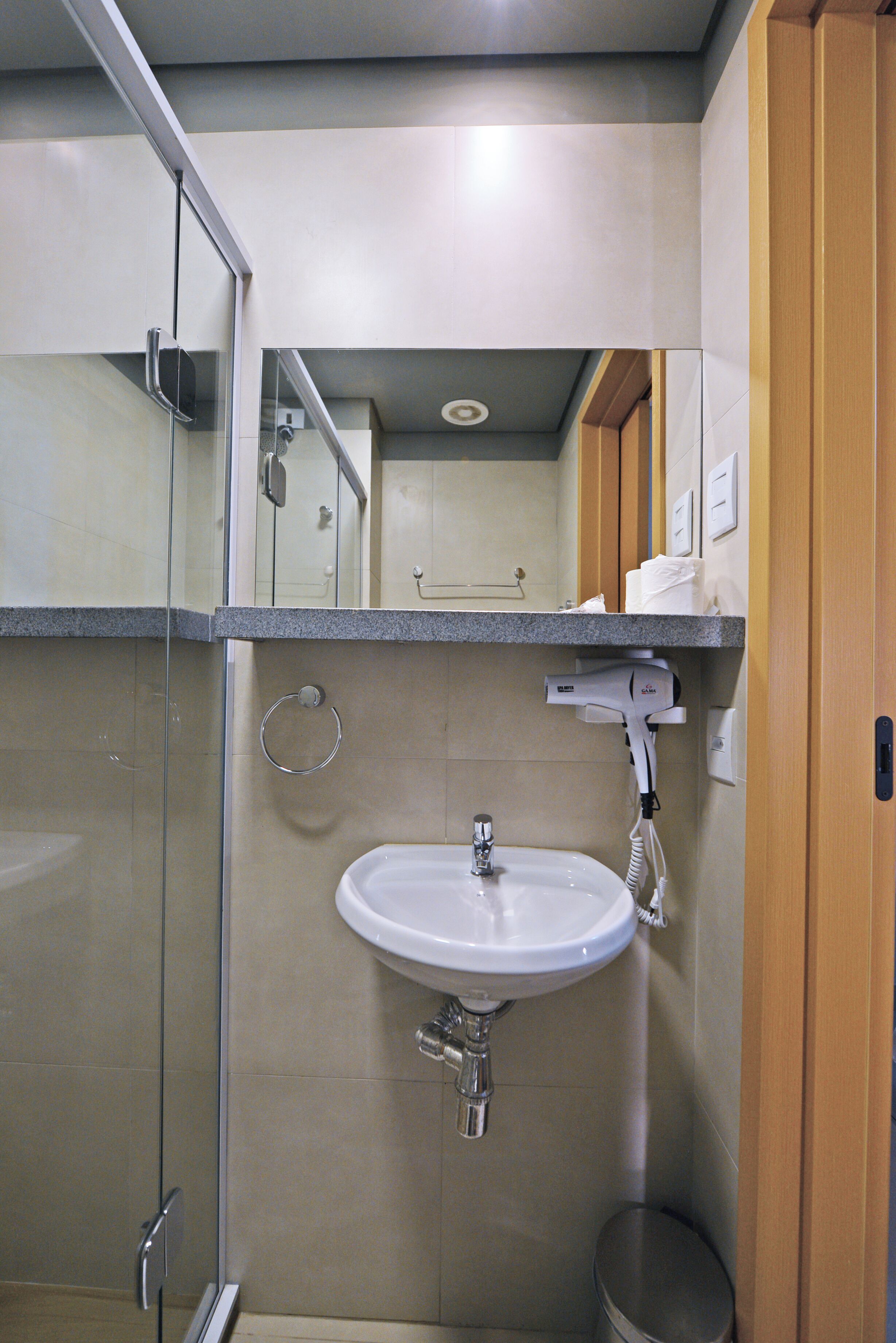 Un bany amb una dutxa envidriada, un lavabo amb mirall i un vàter.