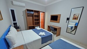 Une chambre d’hôtel avec deux lits, un bureau, une chaise, une armoire, une télévision et un miroir.