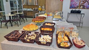 Un buffet proposant divers plats, un coin cuisine et un écran de télévision en arrière-plan.
