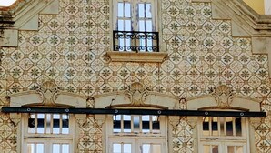 A building with ornate tile patterns, a decorative roof, and a black wrought-iron balcony. - Home Sweet Home - Entire Apartament (Ovar)