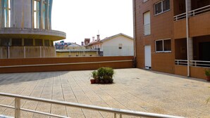 A courtyard with potted plants, a tiled floor, and a building with a balcony. - Home Sweet Home - Entire Apartament (Ovar)