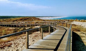 A wooden boardwalk leading to a beach with a clear view of the ocean and dunes in the background. - Home Sweet Home - Entire Apartament (Ovar)