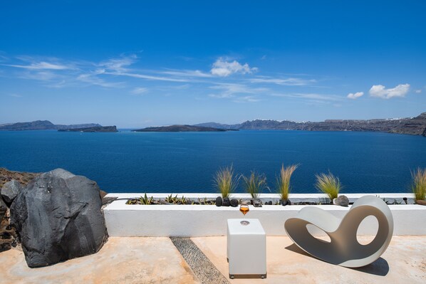 Une vue sur la mer, avec un bâtiment blanc et un grand rocher au premier plan.