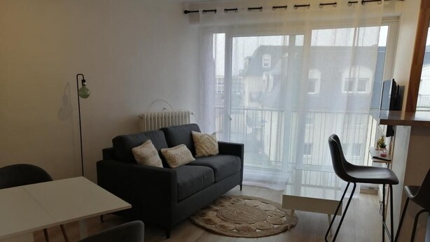 A modern living room with a sofa, a dining table, and chairs. - Appartement Le Conquérant - Caen (Caen)
