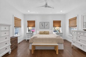 A bedroom with a bed, bedside tables, a bench, and a ceiling fan.