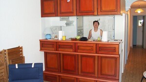 Una cocina con armarios de madera, un ventilador de techo y una persona de pie detrás del mostrador.