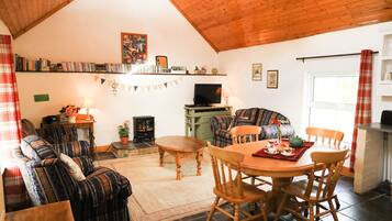 Relax in this inviting living room with a comfortable sofa, dining table, and mounted TV.