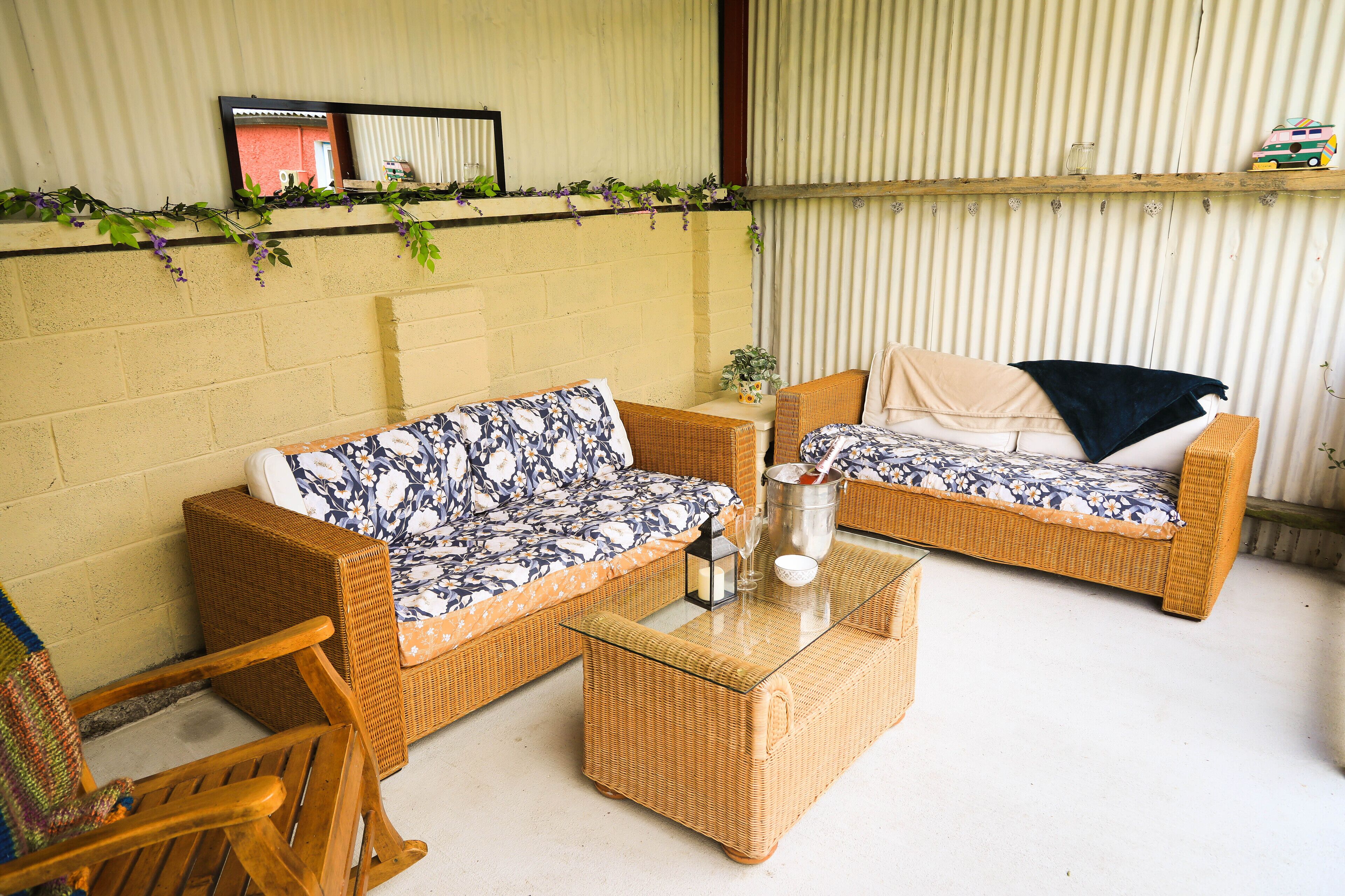 A cozy outdoor seating area with wicker furniture, a glass coffee table, and a small side table.