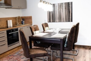 A modern kitchen with a dining table, chairs, and a large painting on the wall.