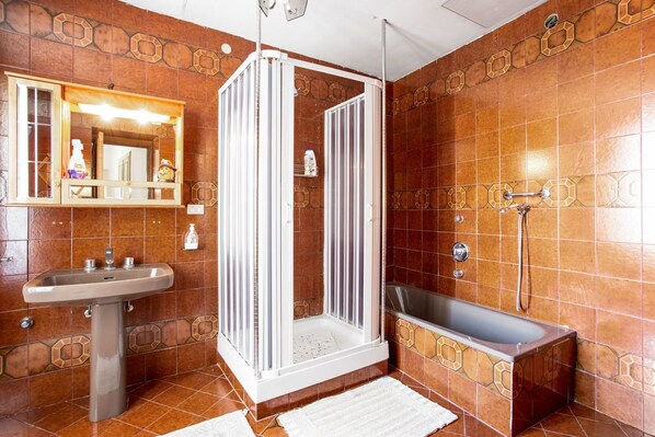 A bathroom with a shower enclosure, a sink, and a bathtub.