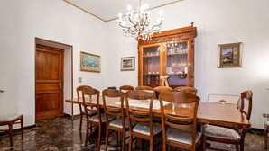 Une salle à manger avec une table et des chaises en bois, un lustre et des tableaux encadrés accrochés aux murs.