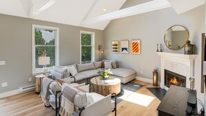 Un salon moderne avec un canapé d’angle, une table basse ronde et une cheminée.